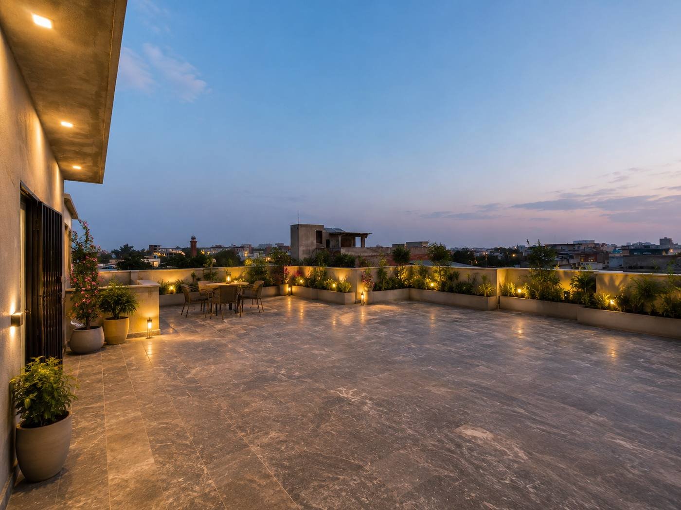 Rooftop terrace with planted borders and patio seating at dusk at Maple Girls' Residence, Lahore